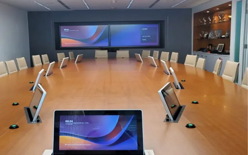Boardroom with a dual-display video wall, an oval table, pop-up seat screens and table microphones, installed by VisionCast