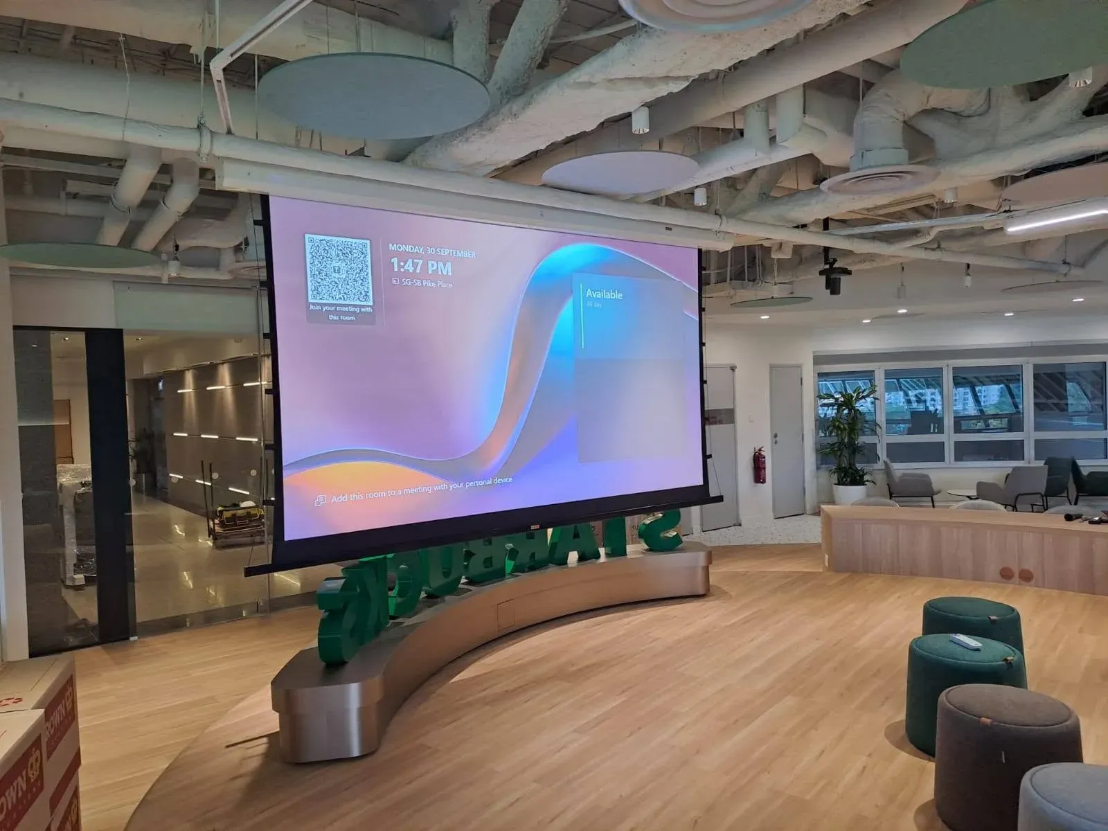 Open-plan townhall in a Singapore office with a large projection screen, installed by VisionCast