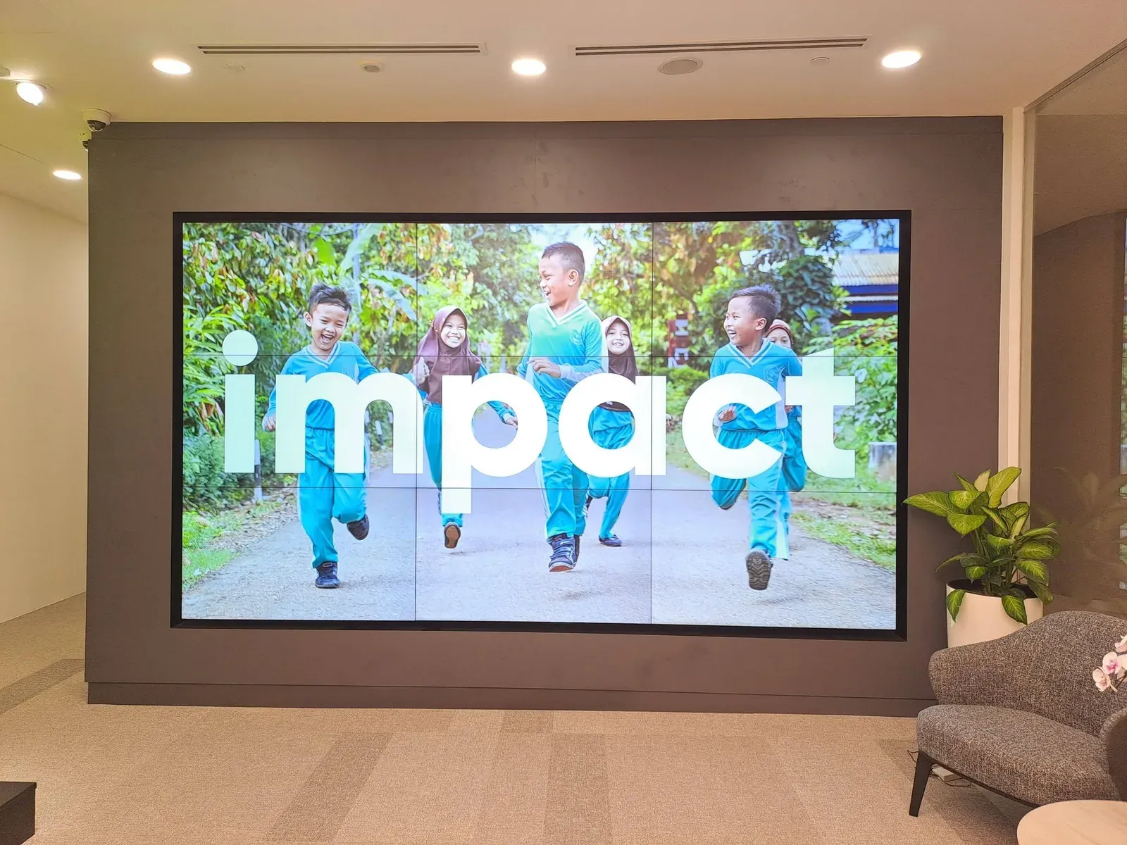 Nine-panel video wall in an office reception, beside lounge seating
